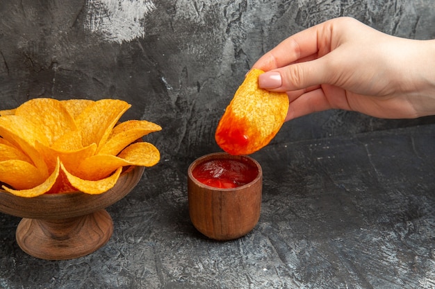 Vista horizontal de papas fritas y tazón de ketchup pequeño en la mesa gris