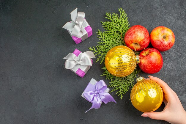 Vista horizontal de regalos y manzanas frescas orgánicas naturales y accesorios de decoración en el lado izquierdo sobre fondo negro