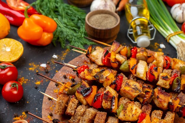 Vista inferior de brochetas de pollo asado sobre tabla de madera y otras cosas en la mesa