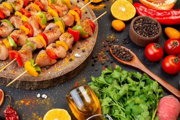 Vista inferior de brochetas de pollo en tablero de madera natural y otros productos en el cuadro negro