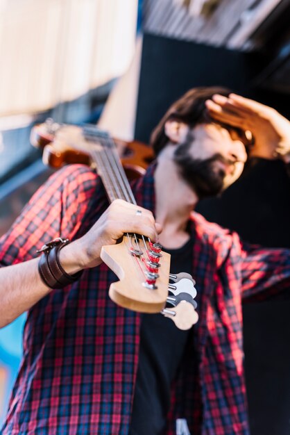 Vista inferior chico sosteniendo la guitarra eléctrica