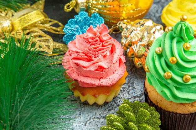 Vista inferior coloridos cupcakes adornos de Navidad sobre fondo gris