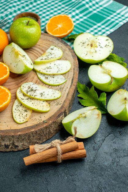Vista inferior cortar manzanas y mandarinas en tablero de madera canela sobre mantel verde sobre mesa oscura