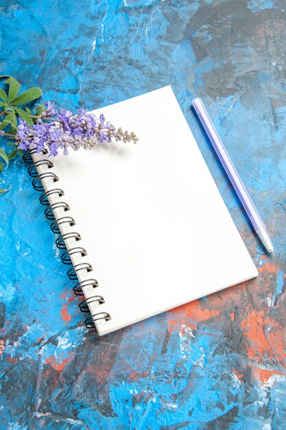 Vista inferior de un cuaderno un bolígrafo sobre la mesa azul