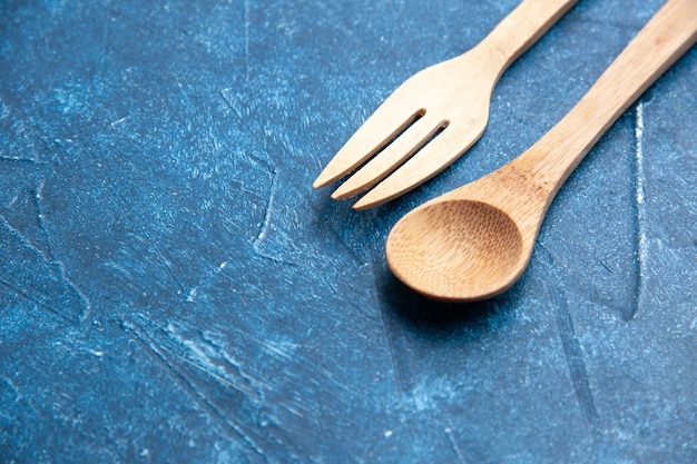 Vista inferior cuchara tenedor de madera en lugar libre de superficie azul