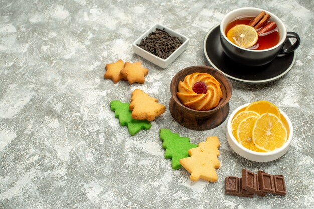 Vista inferior cuencos de galletas de té de limón y canela con rodajas de limón y chocolate en el espacio de copia de la superficie gris