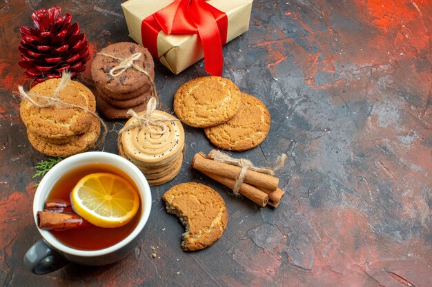 Vista inferior diferentes galletas atadas con una cuerda taza de té sobre fondo rojo oscuro