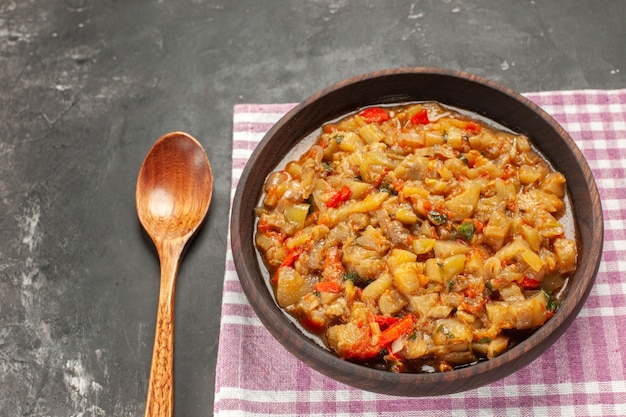 Foto gratuita vista inferior ensalada de berenjena asada en un tazón, cuchara de madera en la mesa oscura