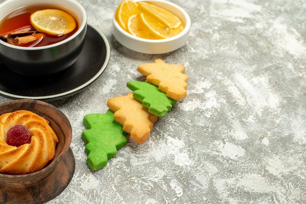 Vista inferior de las galletas del árbol de Navidad taza de té con canela y limón en el espacio de copia de la superficie gris
