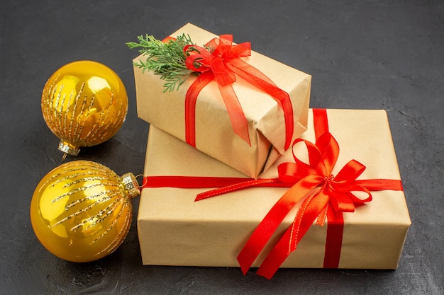 Vista inferior grandes y pequeños regalos de navidad en papel marrón atados con bolas de cinta roja año nuevo sobre fondo oscuro