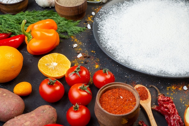 Foto gratuita vista inferior de harina espolvoreada en placa redonda pimiento rojo en polvo en un tazón pequeño tomates eneldo en la mesa