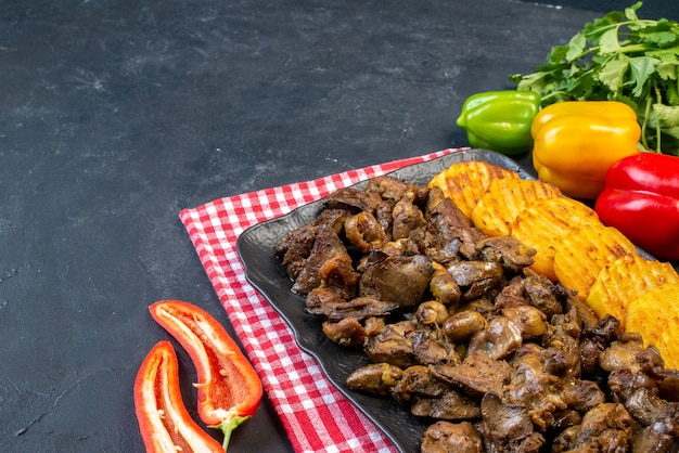 Foto gratuita vista inferior de hígado de pollo frito con patatas en un plato pimientos de color cilantro en la mesa