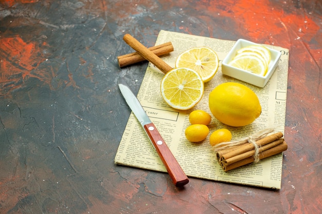 Foto gratuita vista inferior limones frescos cumcuats canela rodajas de limón en un tazón pequeño cuchillo en el periódico en la mesa de color rojo oscuro lugar libre