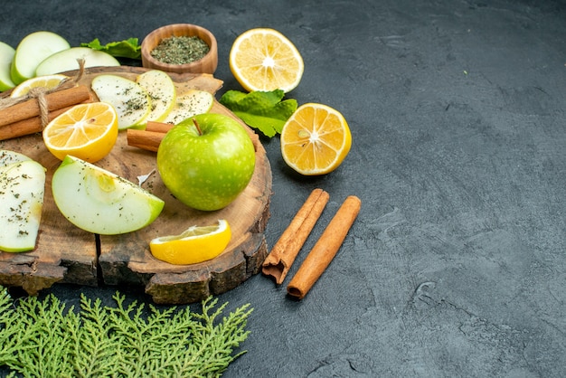 Vista inferior manzana verde fresca palitos de canela rodajas de manzana y limón sobre tablero de madera polvo de menta seca en un tazón ramas de pino en el lugar de copia de mesa negra