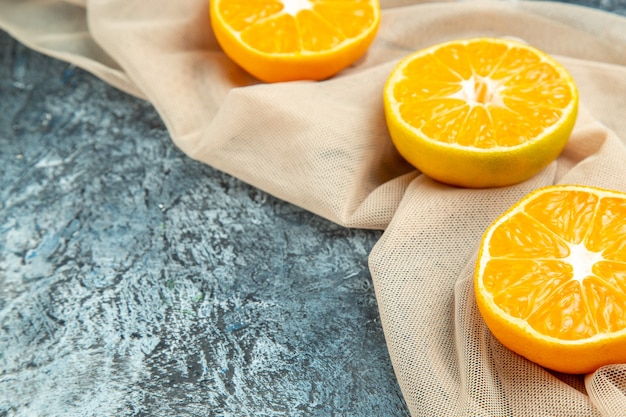 Vista inferior naranjas cortadas en un chal beige en el espacio libre de la superficie oscura