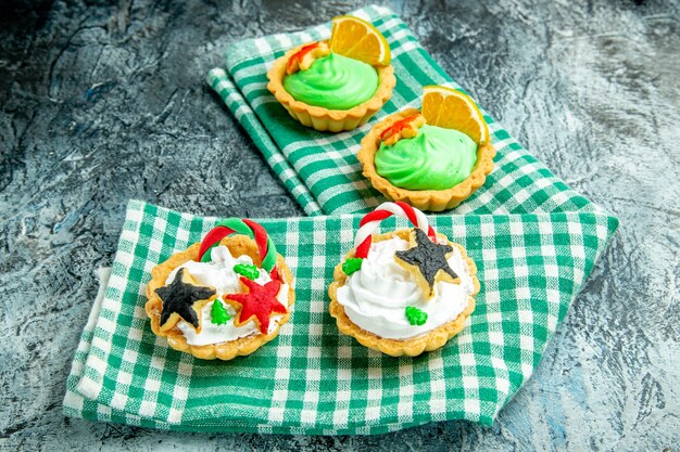 Vista inferior pequeñas tartas de Navidad en mantel a cuadros blanco verde sobre mesa gris