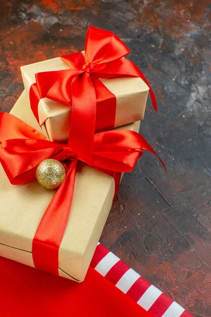 Vista inferior pequeños regalos atados con cinta roja en la mesa de color rojo oscuro