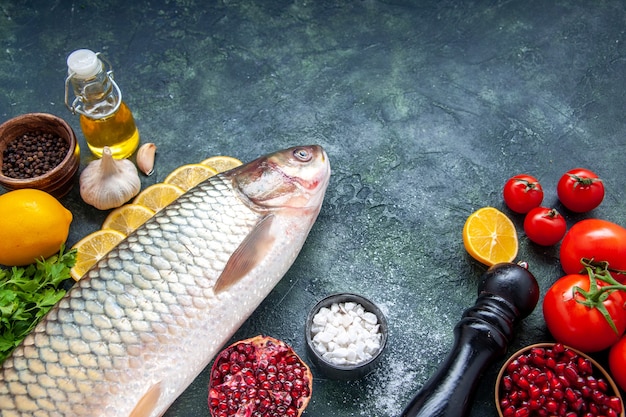 Vista inferior de pescado fresco tomates molinillo de pimienta rodajas de limón en la mesa de la cocina