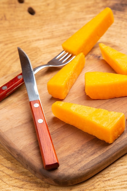 Foto gratuita vista inferior de queso en rodajas de tenedor de queso cuchillo sobre una tabla de cortar sobre la superficie de madera