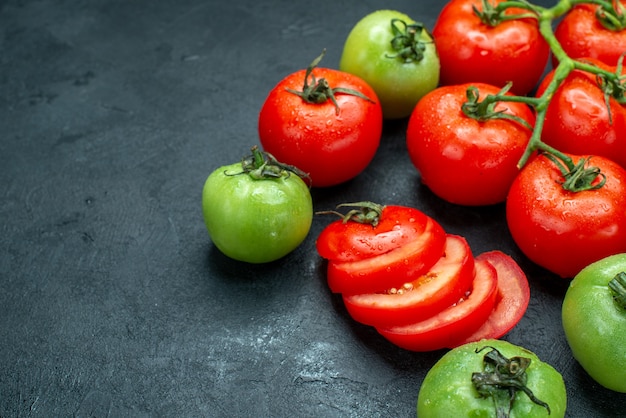 Vista inferior de la rama de tomate tomates picados tomates verdes frescos en el lugar libre de la mesa negra