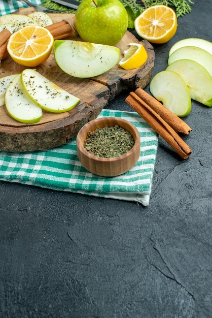 Foto gratuita vista inferior rebanadas de manzana palitos de canela y rodajas de limón manzana sobre tablero de madera en una servilleta verde sobre mesa negra con lugar libre