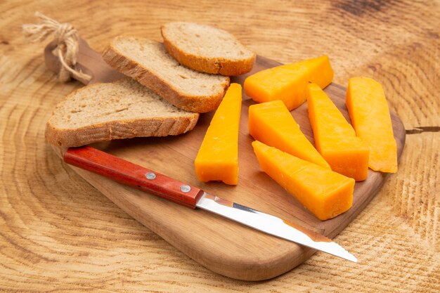 Vista inferior rebanadas de queso rebanadas de pan cuchillo sobre una tabla de cortar sobre la mesa de madera