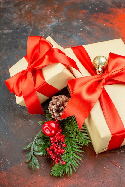 Vista inferior regalos de Navidad atados con cinta roja rama de árbol de Navidad sobre fondo rojo oscuro