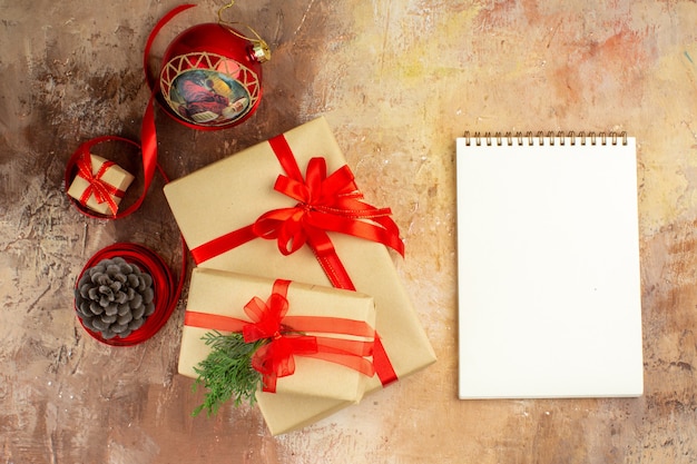 Vista inferior de los regalos de Navidad en la cinta de papel marrón, el árbol de Navidad de juguete en el periódico en la oscuridad.