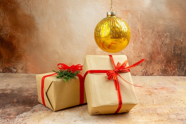 Vista inferior de los regalos de Navidad en la cinta de papel marrón, el árbol de Navidad de juguete en el periódico en la oscuridad.