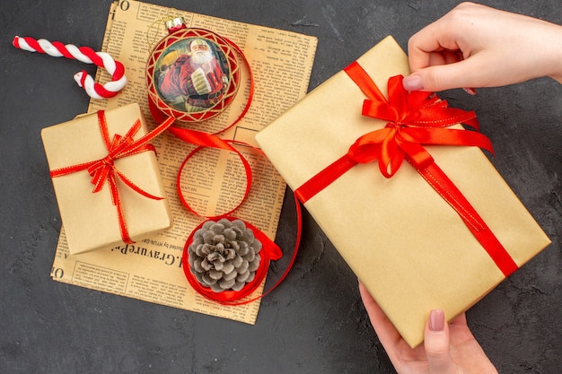 Vista inferior de regalos de Navidad en cinta de papel marrón juguete de árbol de Navidad en periódico sobre fondo oscuro