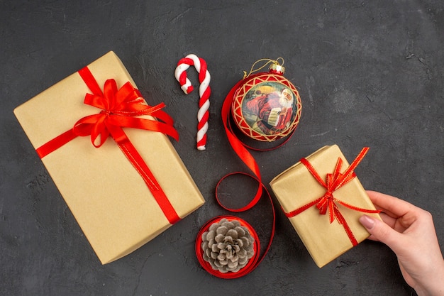 Vista inferior de regalos de Navidad en cinta de papel marrón juguete de árbol de Navidad en periódico sobre fondo oscuro