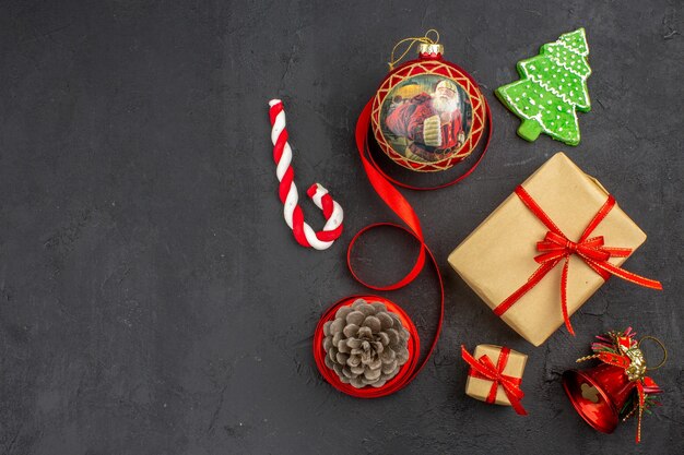 Vista inferior de regalos de Navidad en cinta de papel marrón juguete de árbol de Navidad en periódico sobre fondo oscuro