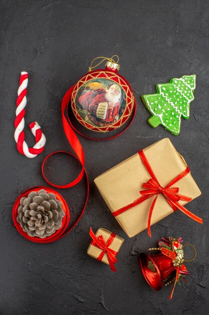 Vista inferior de regalos de Navidad en cinta de papel marrón juguete de árbol de Navidad en periódico sobre fondo oscuro