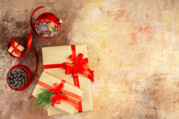 Vista inferior de regalos de Navidad en cinta de papel marrón juguete de árbol de Navidad en periódico sobre fondo oscuro