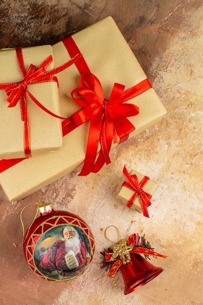 Vista inferior de regalos de Navidad en cinta de papel marrón juguete de árbol de Navidad en periódico sobre fondo oscuro