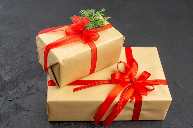 Vista inferior de regalos de Navidad grandes y pequeños en papel marrón atado con cinta roja en la oscuridad