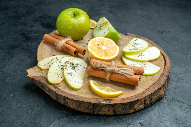 Vista inferior rodajas de manzana canela y rodajas de limón sobre tablero de madera con manzana seca en polvo de menta sobre fondo negro