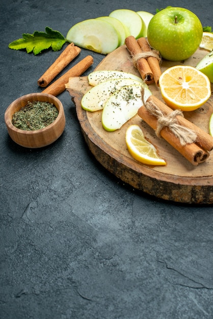 Foto gratuita vista inferior de rodajas de manzana manzana palitos de canela rodajas de limón sobre tablero de madera con polvo de menta seca en el lugar de copia de tierra negra