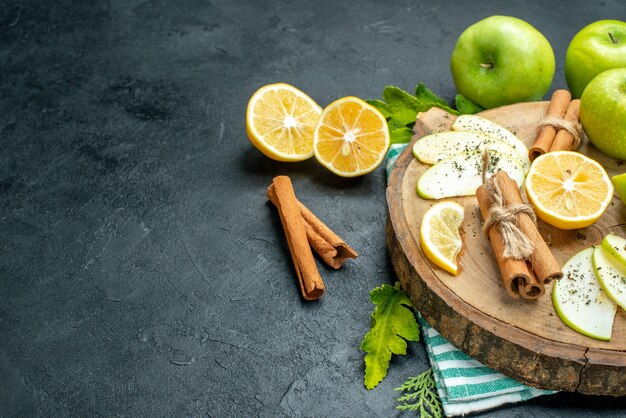 Vista inferior rodajas de manzana palitos de canela y rodajas de limón sobre tablero de madera cortar limones manzanas en mesa negra con espacio libre