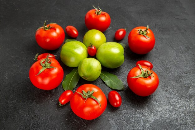 Vista inferior rojo verde y tomates cherry y hojas de laurel sobre fondo oscuro