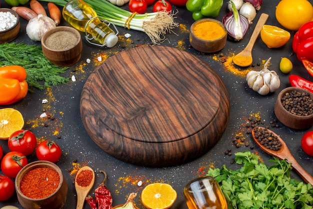 Vista inferior de la tabla de madera redonda especias en tazones pequeños tomates ajo cilantro eneldo limón en la mesa