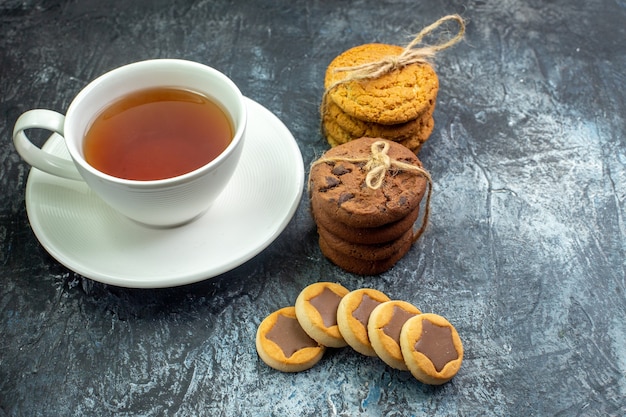 Vista inferior de la taza de té galletas galletas atadas con una cuerda en el lugar libre de la mesa gris