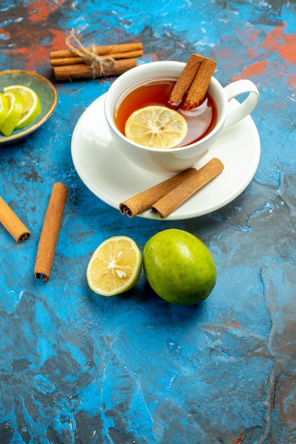 Vista inferior de una taza de té con limón y canela sobre la superficie azul roja