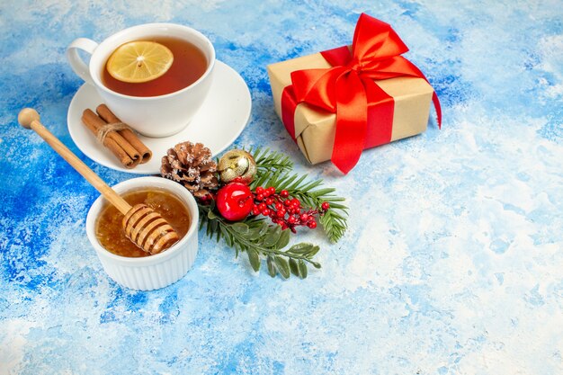 Vista inferior taza de té miel regalo rama de árbol de Navidad en mesa azul espacio libre