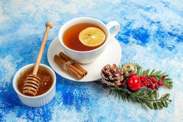 Vista inferior de la taza de té de miel en un tazón de fuente de la rama de un árbol de Navidad en el cuadro azul