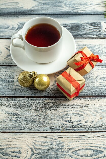 Vista inferior de una taza de té regalos árbol de Navidad juguetes sobre fondo de madera