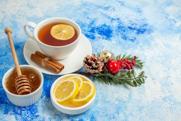 Vista inferior de la taza de té de rodajas de limón miel en un tazón xms ramas de los árboles en el cuadro azul