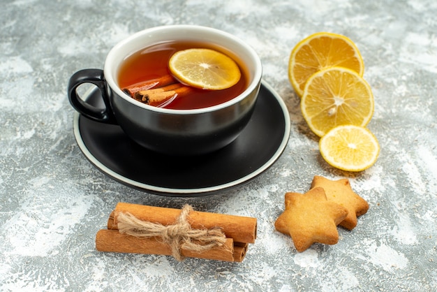 Foto gratuita vista inferior de una taza de té rodajas de limón palitos de canela sobre superficie gris