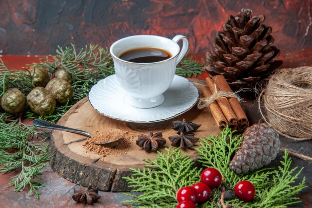 Vista inferior de una taza de té en el tablero de madera, palitos de canela, piñas, anís en la oscuridad