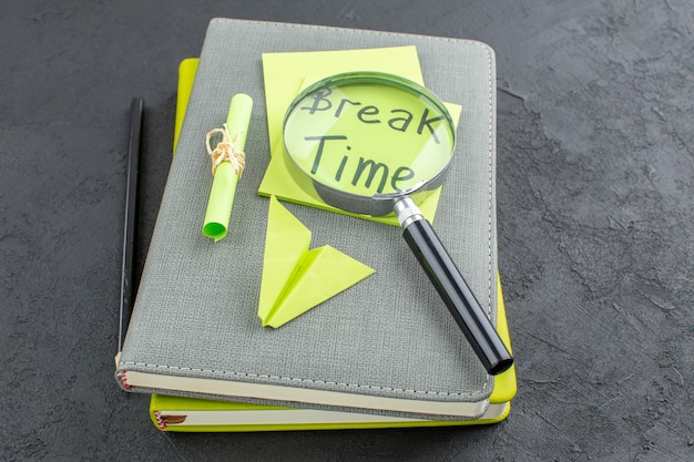 Vista inferior del tiempo de descanso escrito en notas adhesivas lupa lápiz negro en blocs de notas en la mesa oscura